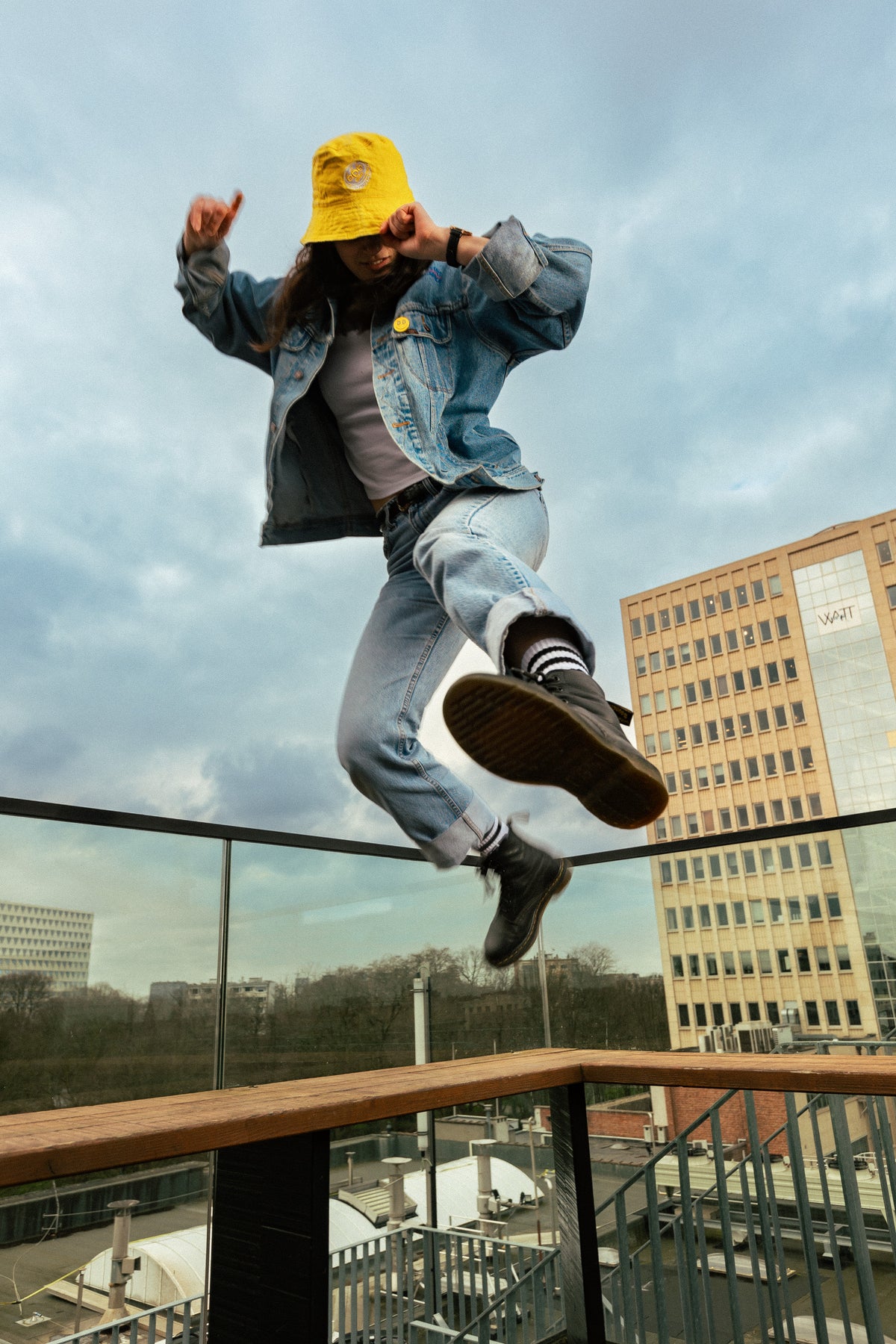 Woman wearing yellow bucket hat jumping in the air