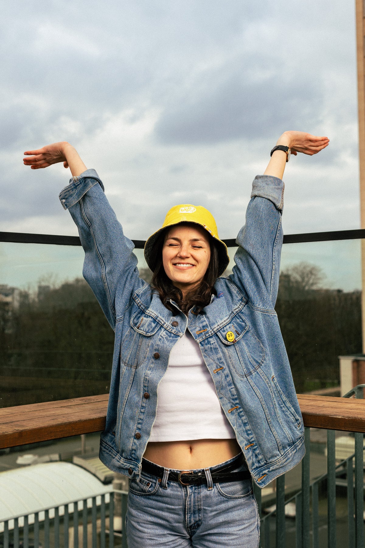 woman wearing yellow Duvel 6.66 bucket hat with arms raised